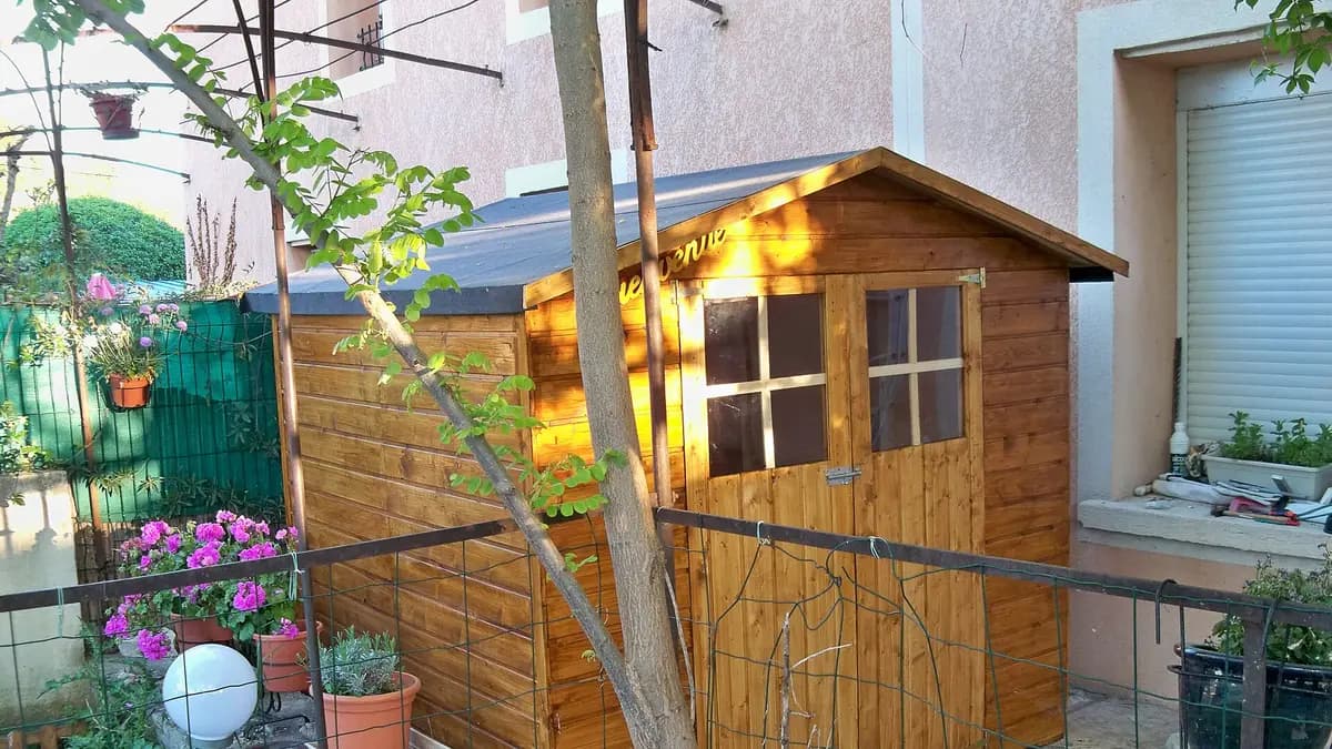 Abri de jardin en bois installé au fond d’un jardin fleuri